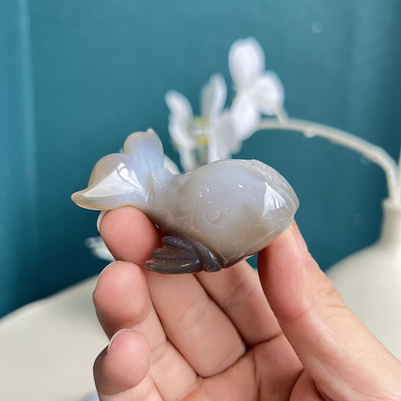 White agate crystal dolphin carving held in hand showing size perspective