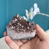 Amethyst crystal cluster displayed with white orchids on table