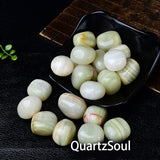 Green aventurine tumbled crystals arranged in black dish showing various sizes and mineral inclusions