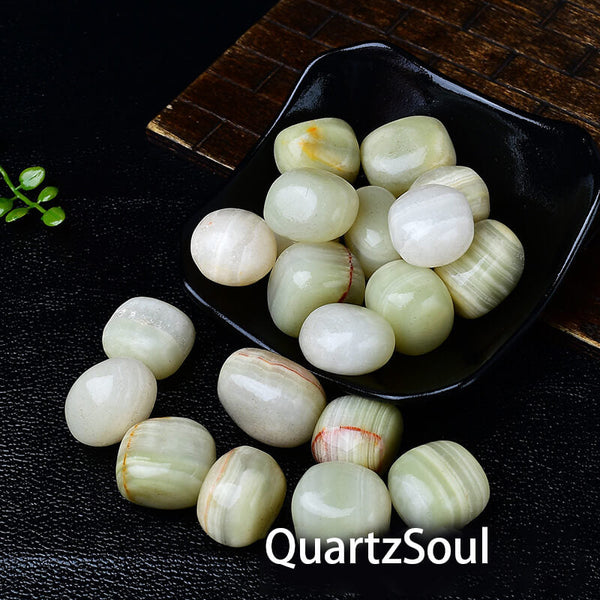 Green aventurine tumbled crystals arranged in black dish showing various sizes and mineral inclusions