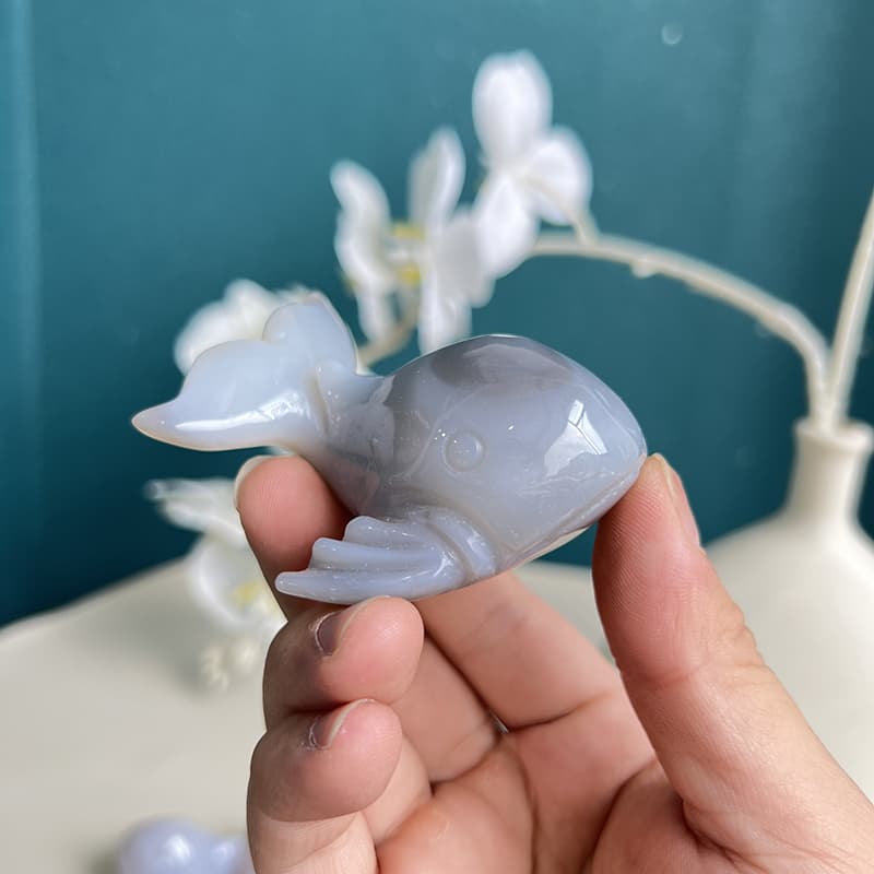 Blue agate whale crystal carving shown in palm for size reference