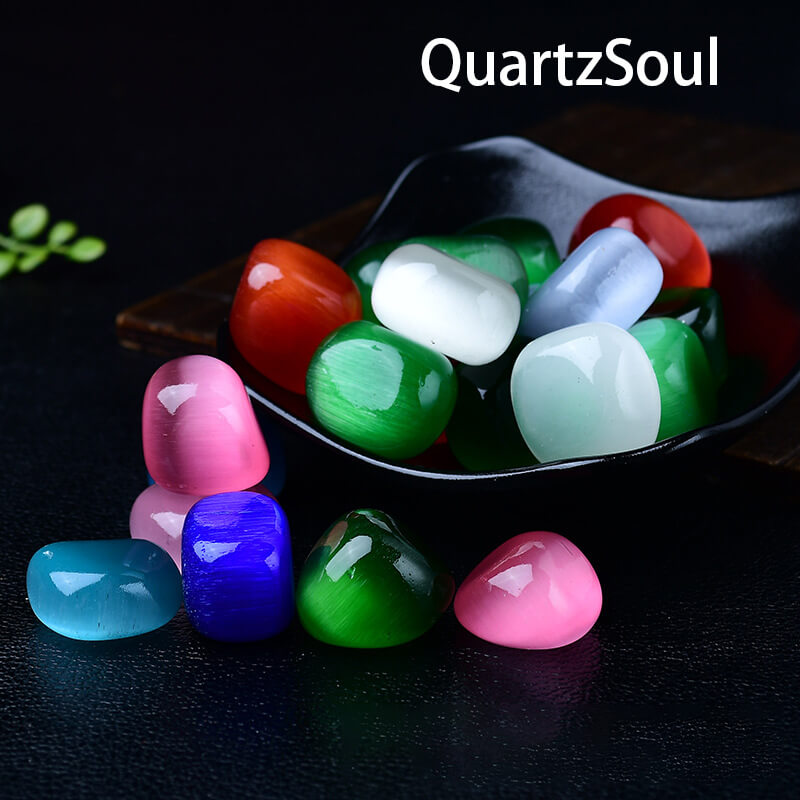 Colorful cat's eye tumbled gemstones displayed in decorative bowl showing chatoyancy