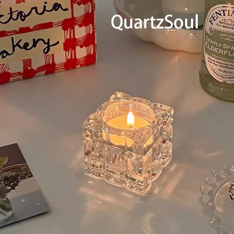 Crystal cube candle holder with lit tealight creating ambient glow on white surface