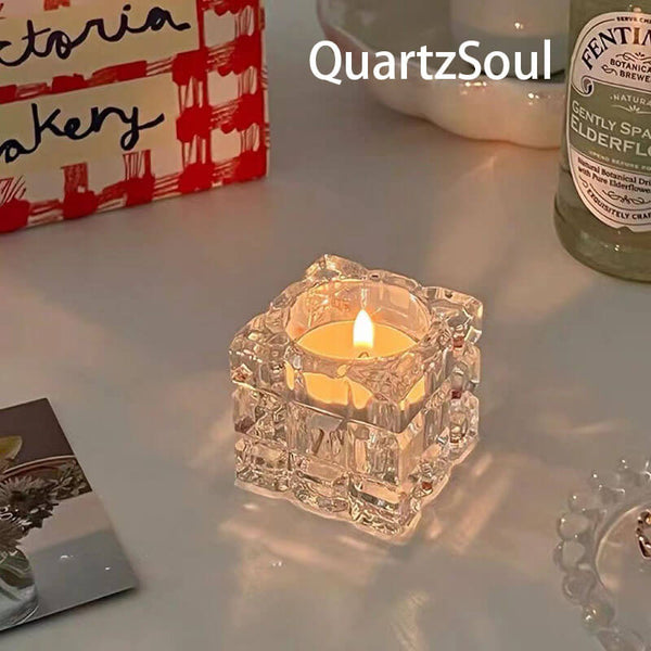 Crystal cube candle holder with lit tealight creating ambient glow on white surface