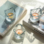 Crystal clear glass candle holder with wavy organic design and lit tealight candle