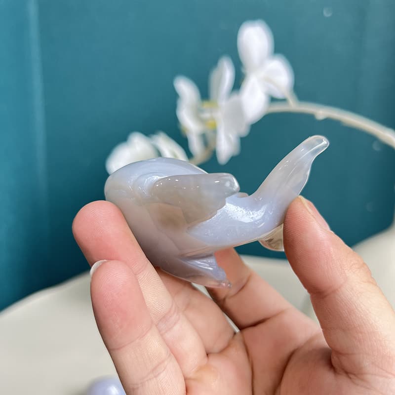 Person holding dolphin agate crystal carving showing scale