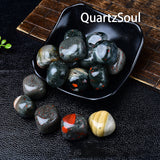 Dragon Bloodstone tumbled gemstones in decorative black bowl showing various sizes and patterns