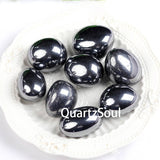 Natural Hematite tumbled stones with metallic silver-gray luster displayed on white plate