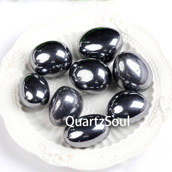 Natural Hematite tumbled stones with metallic silver-gray luster displayed on white plate