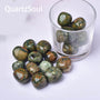 Natural Kambaba Jasper tumbled stones in glass container showing green and orbicular patterns