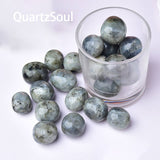 Natural labradorite tumbled stones in glass container showing blue and green flash