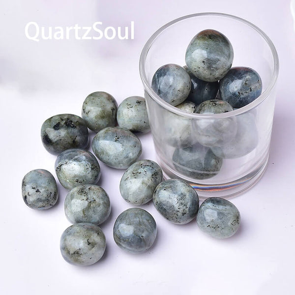 Natural labradorite tumbled stones in glass container showing blue and green flash