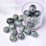 Natural labradorite tumbled stones in glass container showing blue and green flash