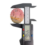 Digital caliper measuring height of pink Rhodonite crystal carving at 30.6mm
