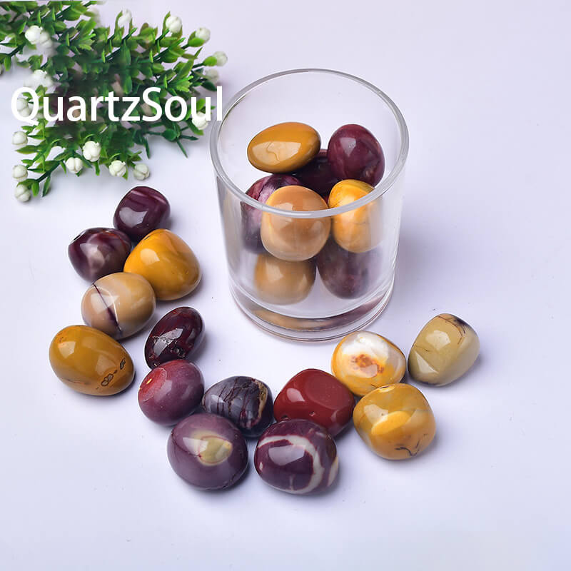 Natural Mookaite Jasper tumbled stones collection in glass container showing burgundy and golden colors