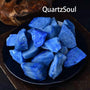 Natural raw Blue Aventurine crystal chunks displayed on black plate with vibrant blue color