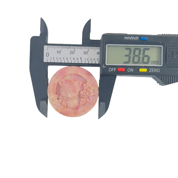 Side view of natural rhodonite bear carving showing stone patterns