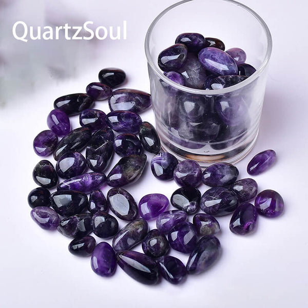 Premium amethyst tumbled stones displayed in glass container showing purple crystal variety