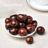 Collection of polished Red Obsidian tumbled stones displayed on white plate