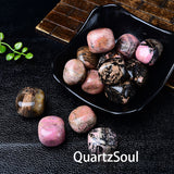 Natural rhodochrosite tumbled stones in black bowl showing pink and black patterns