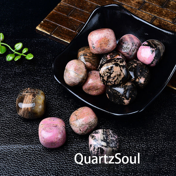 Natural rhodochrosite tumbled stones in black bowl showing pink and black patterns