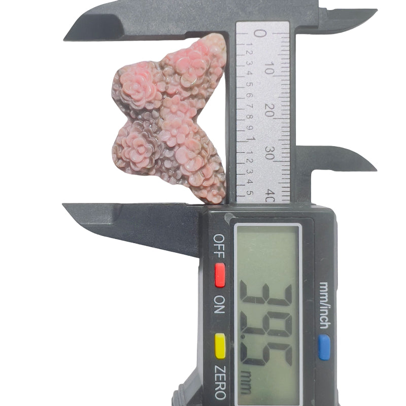 Rhodonite butterfly crystal carving held in palm showing size and natural stone texture