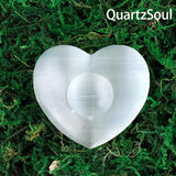 White selenite heart palm stone with center depression on moss background