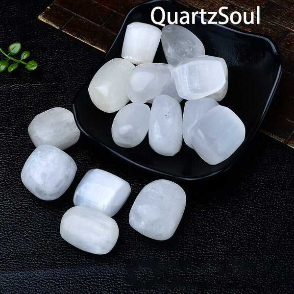 Selenite tumbled stones in black dish showing smooth polished surfaces and natural luminosity