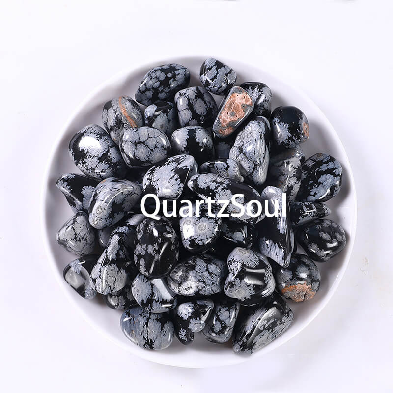 Collection of Snowflake Obsidian tumbled stones in white ceramic bowl showing various sizes
