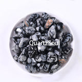 Collection of Snowflake Obsidian tumbled stones in white ceramic bowl showing various sizes