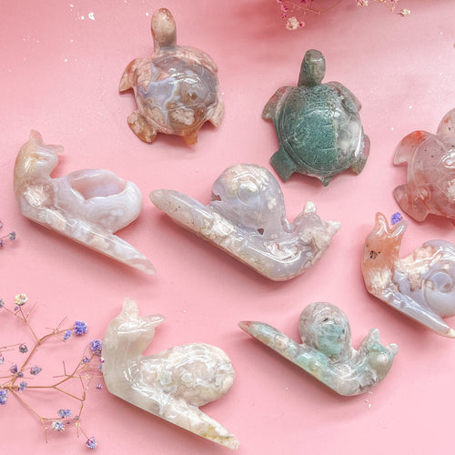 Assorted natural crystal animal carvings on pink background