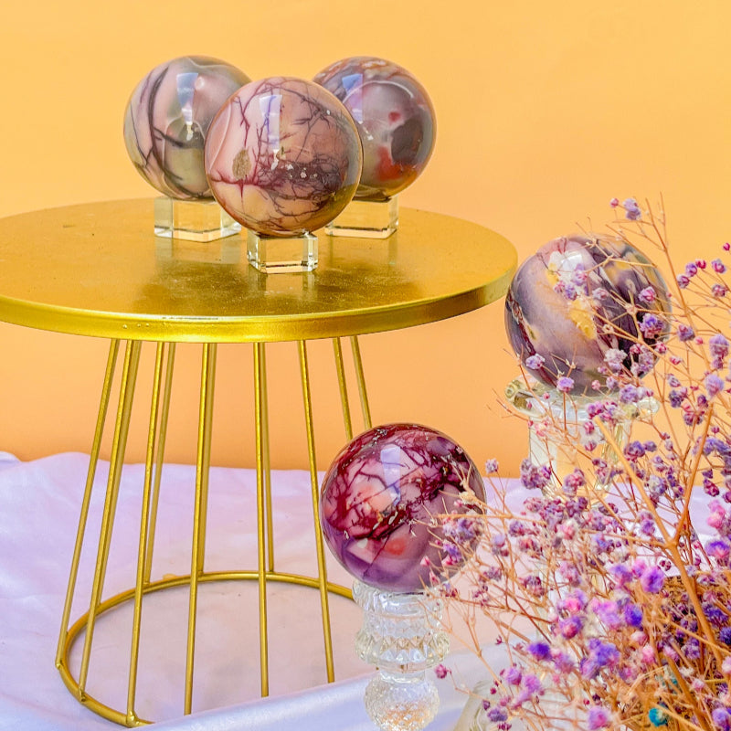 Premium Moonkaite Crystal Spheres on Gold Display Stand with Purple Flowers