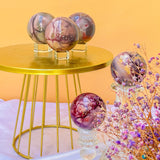 Premium Moonkaite Crystal Spheres on Gold Display Stand with Purple Flowers