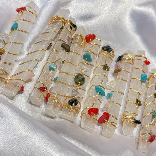 Selenite crystal wands with wire wrapped gemstone accents on white silk background