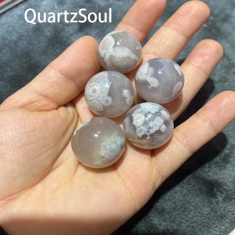 Premium Blossom Agate spheres displayed in hand showing translucent patterns wholesale crystal supply