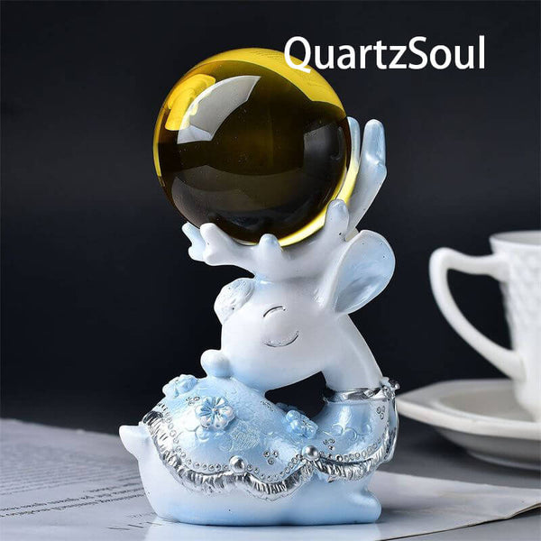 Hand-shaped blue crystal ball stand with elegant silver detailing holding amber sphere