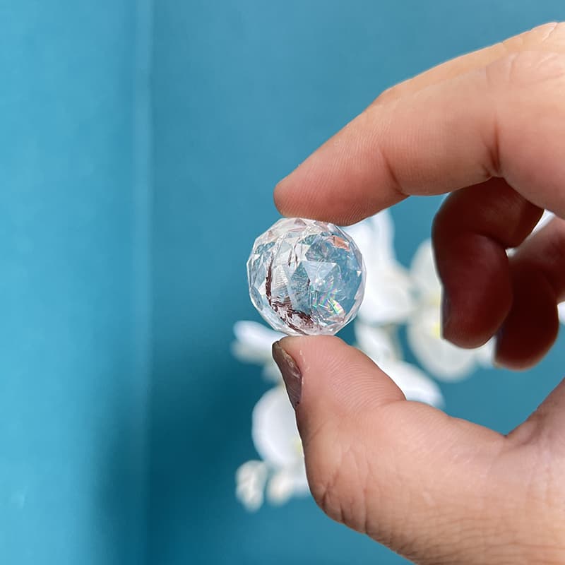 Clear Quartz carved mini sphere displaying internal clarity and rainbow reflections