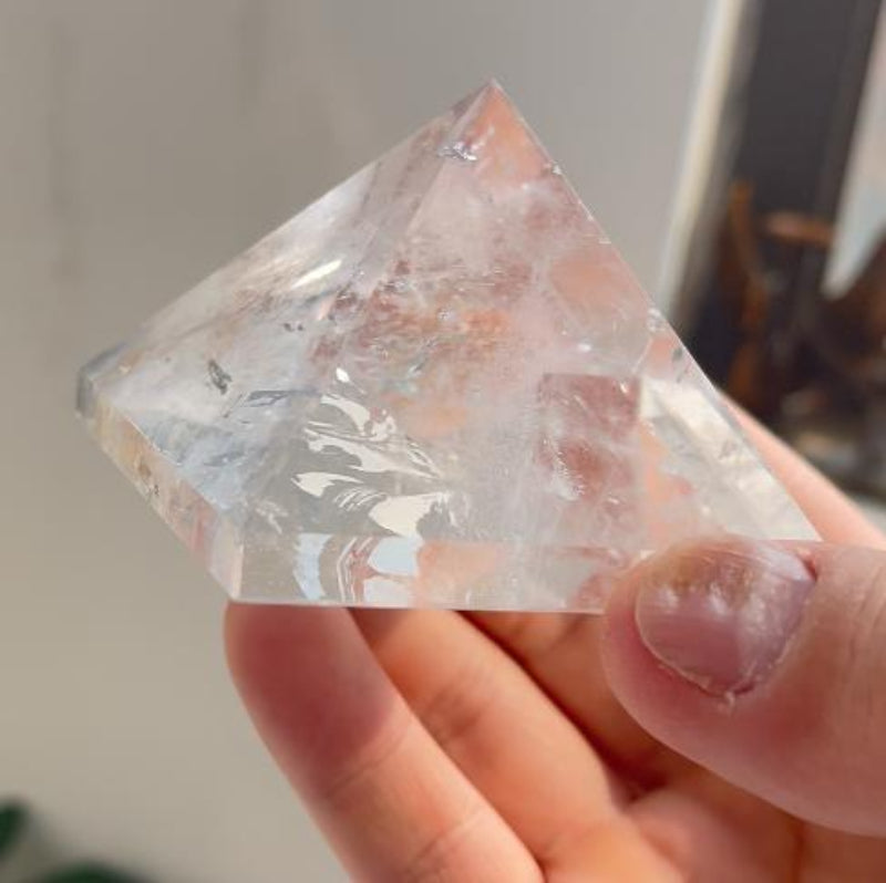 Natural clear quartz pyramid displayed on a base