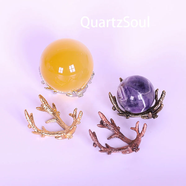 Amethyst and citrine crystal spheres displayed on antler stands in multiple finishes