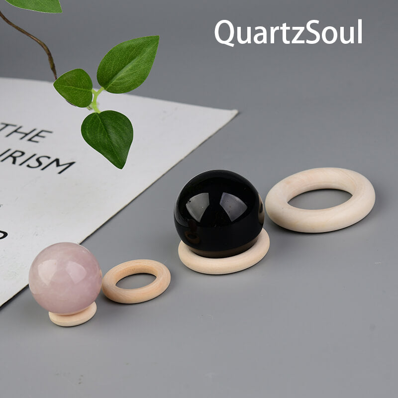Pink and black crystal spheres displayed on elegant wooden circular stands