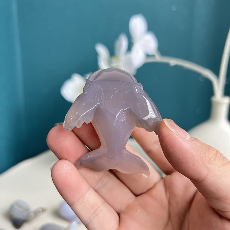 Agate dolphin crystal carving shown in hand to demonstrate size
