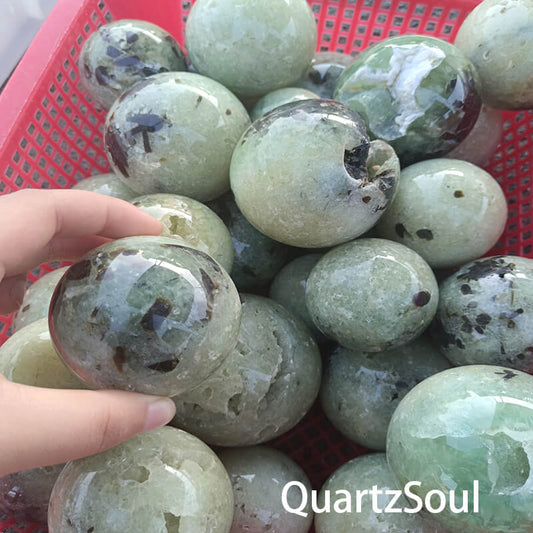 Polished green prehnite crystal sphere showing characteristic inclusions