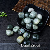 Green Rutilated Quartz tumbled stones displayed in a decorative bowl showing size and texture
