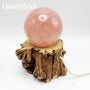 Illuminated wooden tree crystal sphere stand displaying rose quartz ball with natural wood base