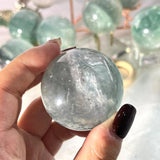 Light green fluorite crystal sphere on wooden display stand
