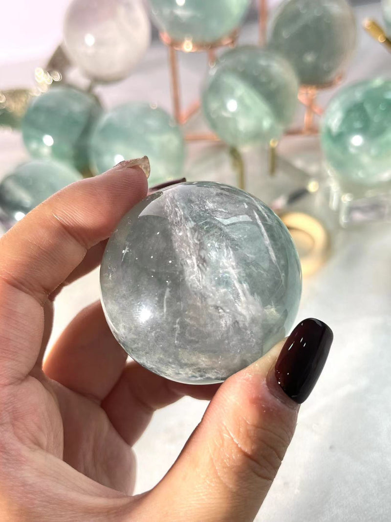 Light green fluorite crystal sphere on wooden display stand