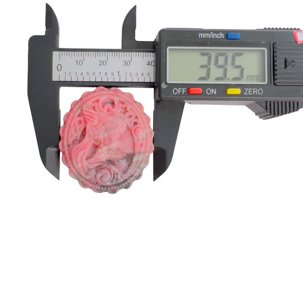 Pink rhodonite crystal carving held in palm showing scale