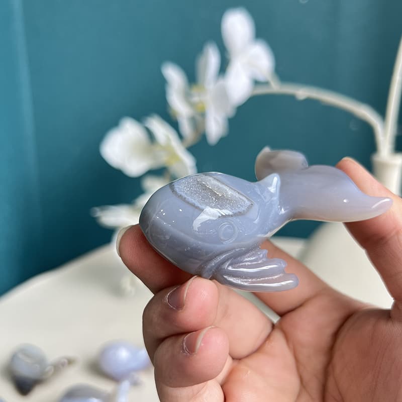 Natural agate crystal whale carving showing size perspective in hand