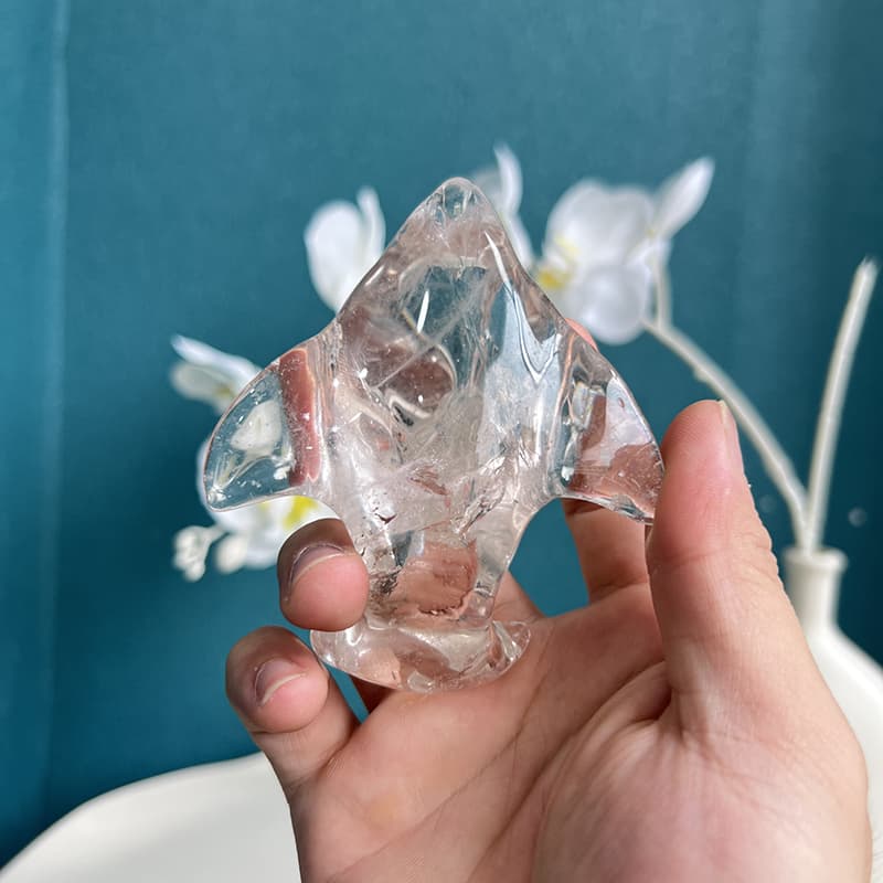 Clear quartz dolphin crystal carving displayed on wooden stand