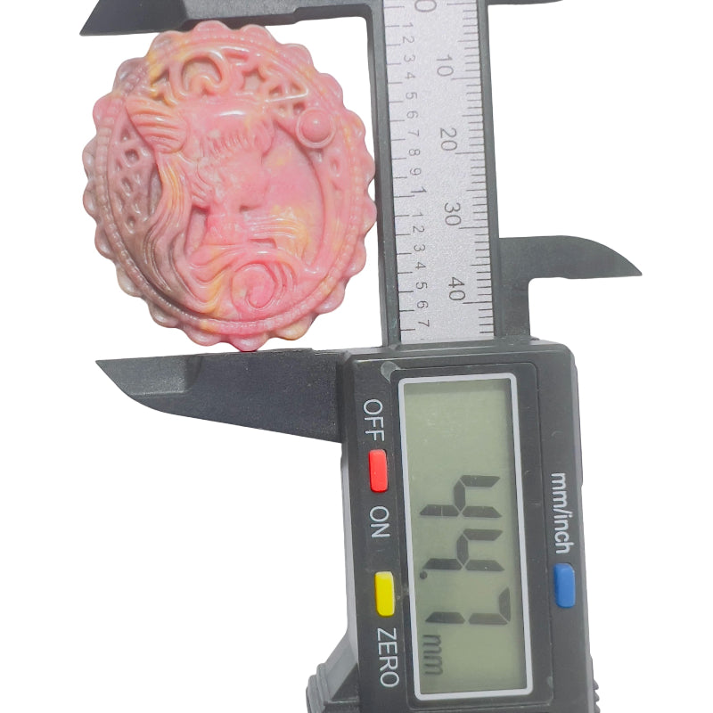 Pink rhodonite crystal carved medallion with magical girl pattern in natural light